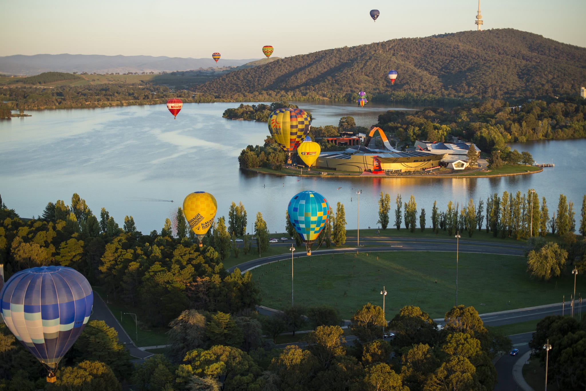 hot air balloons drift by the National Museum of Australia